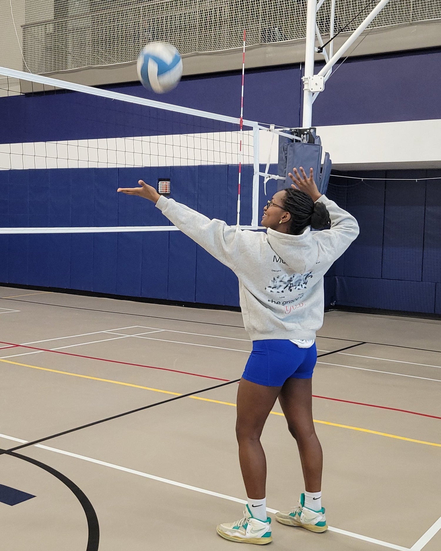 Person playing volleyball indoors, jumping to hit the ball